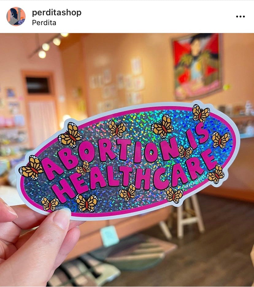 A vinyl bumper sticker with glitter detail, featuring butterflies surrounding the text 'Abortion is Healthcare’. - The Peach Fuzz