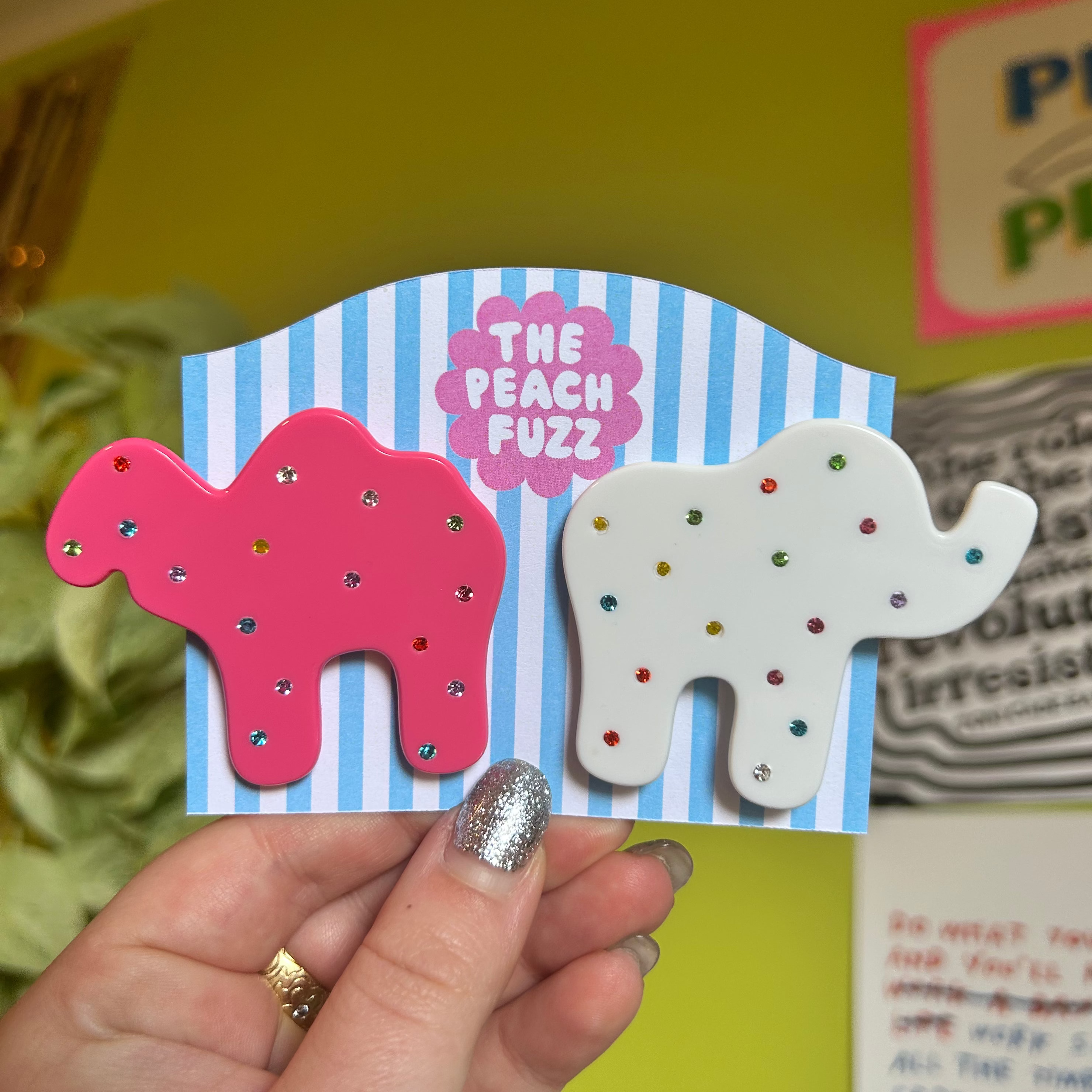 "Animal Cracker Hair Clip Set" features two clips (one pink camel, one white elephant) The "sprinkles" are made with multi color gemstones! Each clip measures 6 cm.