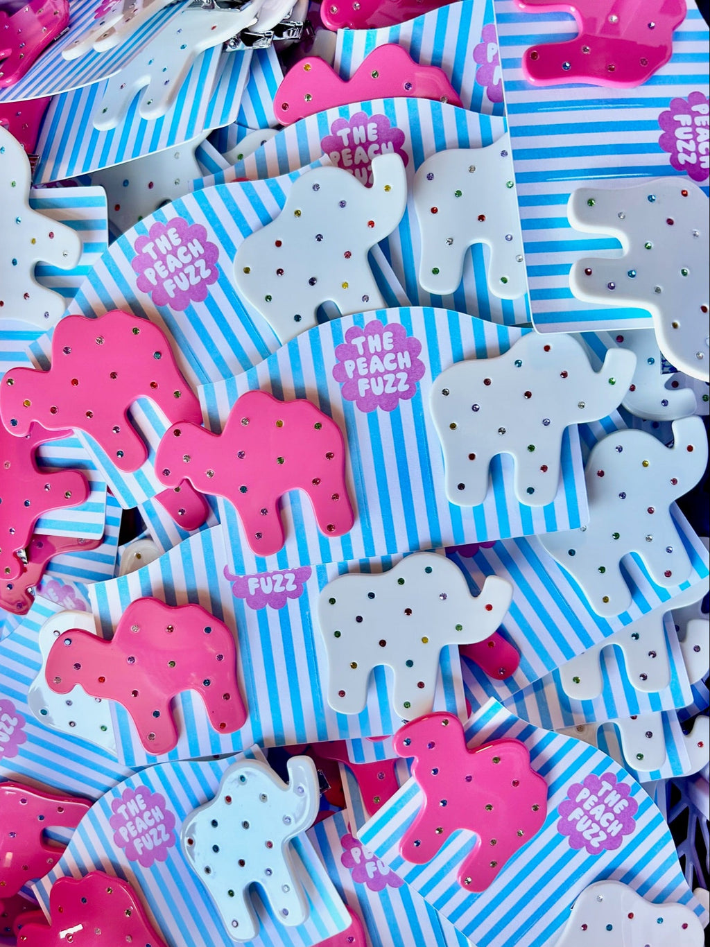 "Animal Cracker Hair Clip Set" features two clips (one pink camel, one white elephant) The "sprinkles" are made with multi color gemstones! Each clip measures 6 cm.