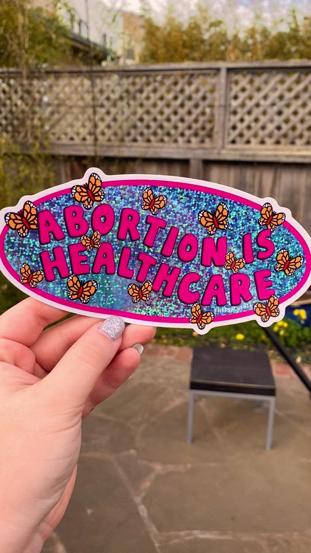 A vinyl bumper sticker with glitter detail, featuring butterflies surrounding the text 'Abortion is Healthcare’. - The Peach Fuzz