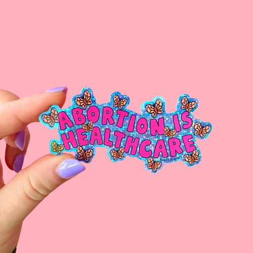 “Abortion Is Healthcare” Vinyl sticker with glossy finish and glitter detail. Measures 3.3 x 1.7 inches. - The Peach Fuzz