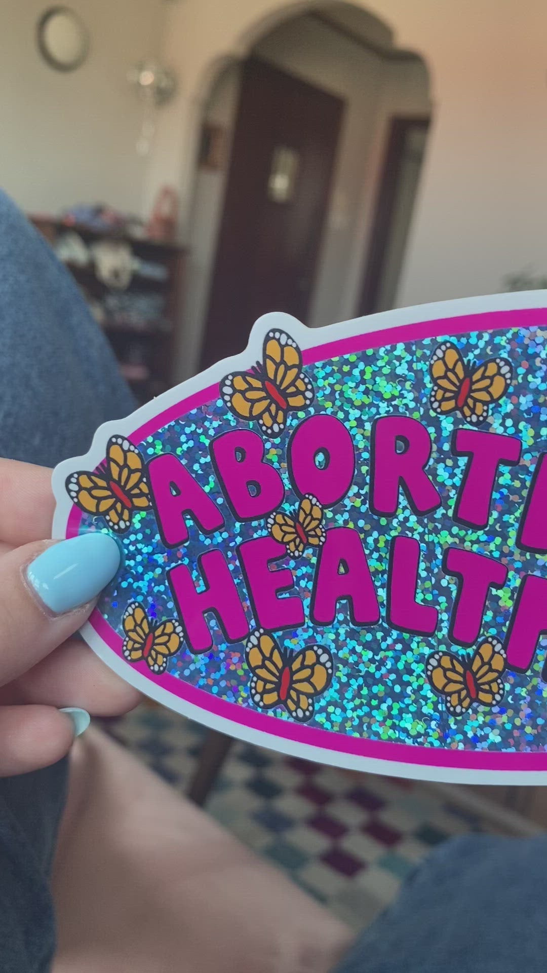 A vinyl bumper sticker with glitter detail, featuring butterflies surrounding the text 'Abortion is Healthcare’. - The Peach Fuzz
