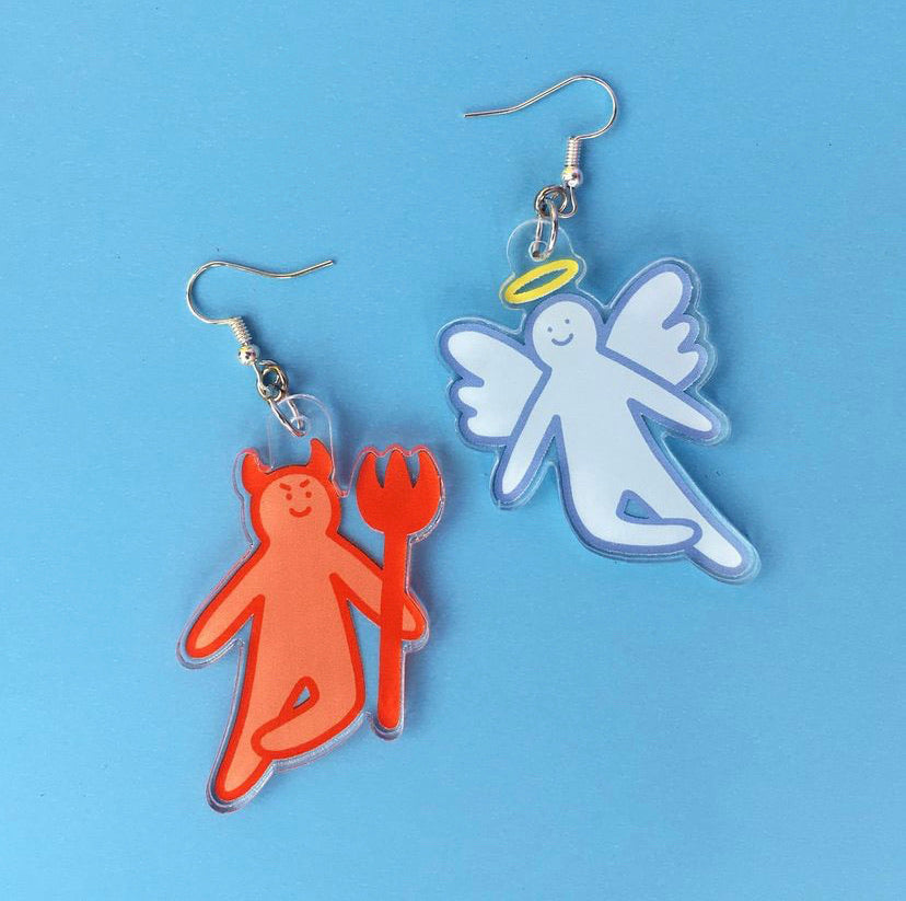 A pair of earrings made of acrylic featuring a poorly drawn angel and devil